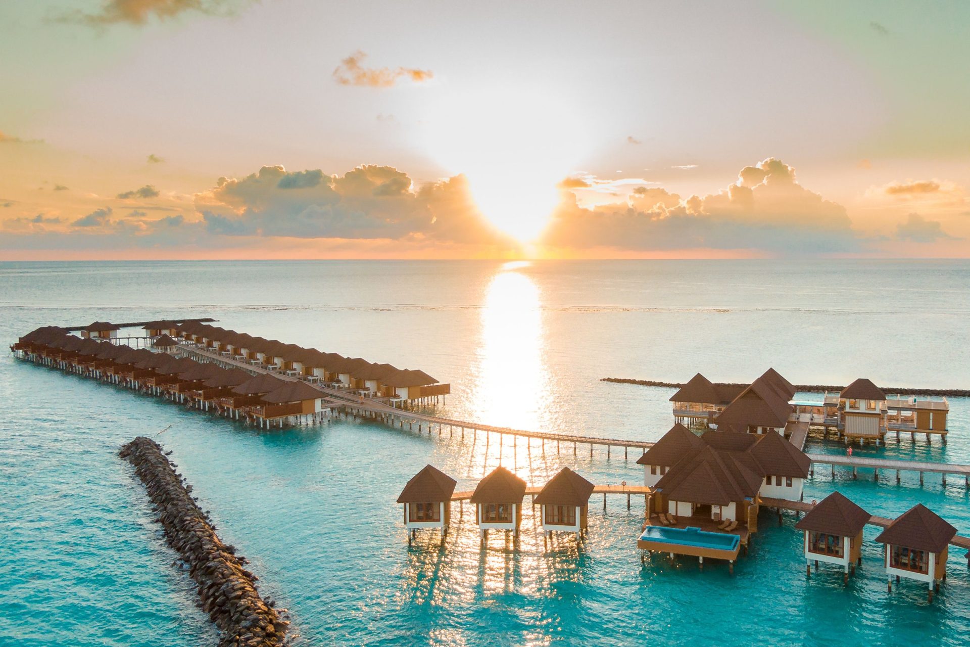 Captivating aerial view of luxurious Maldives overwater villas at sunrise, perfect for a serene vacation.