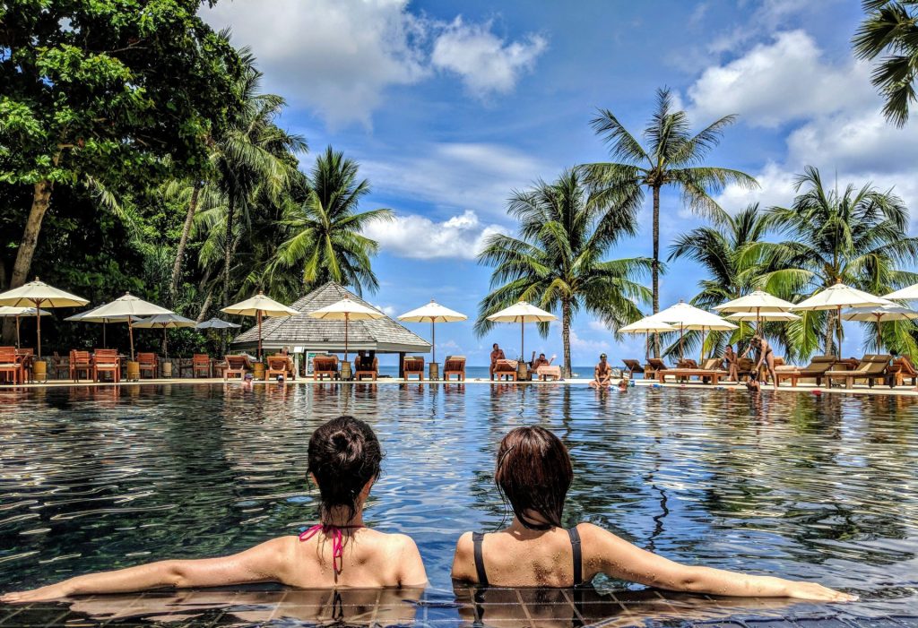 two woman leaning on inground pool tile