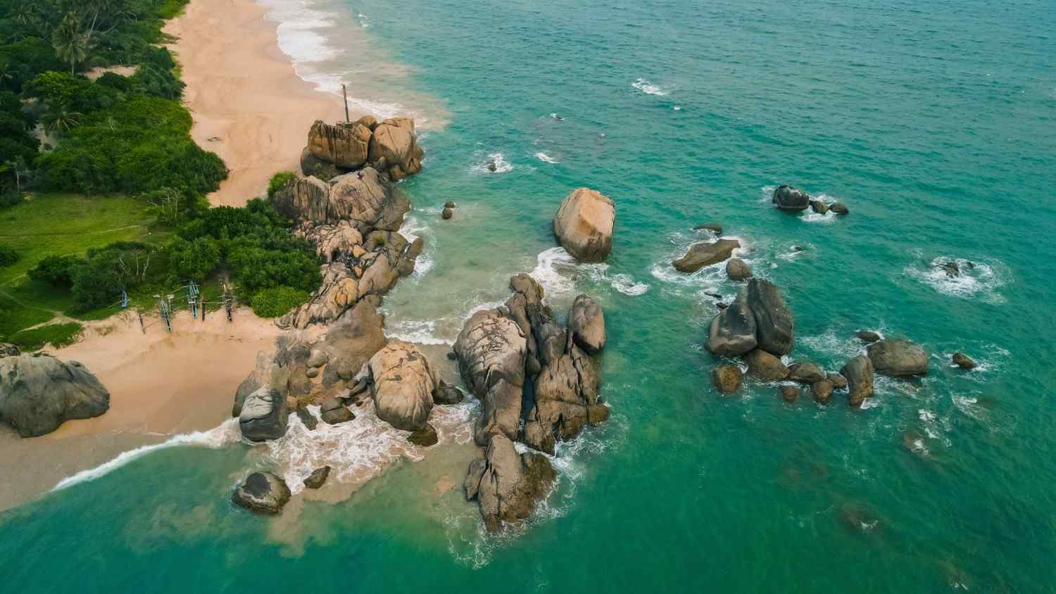 an aerial view of a beach with rocks and water