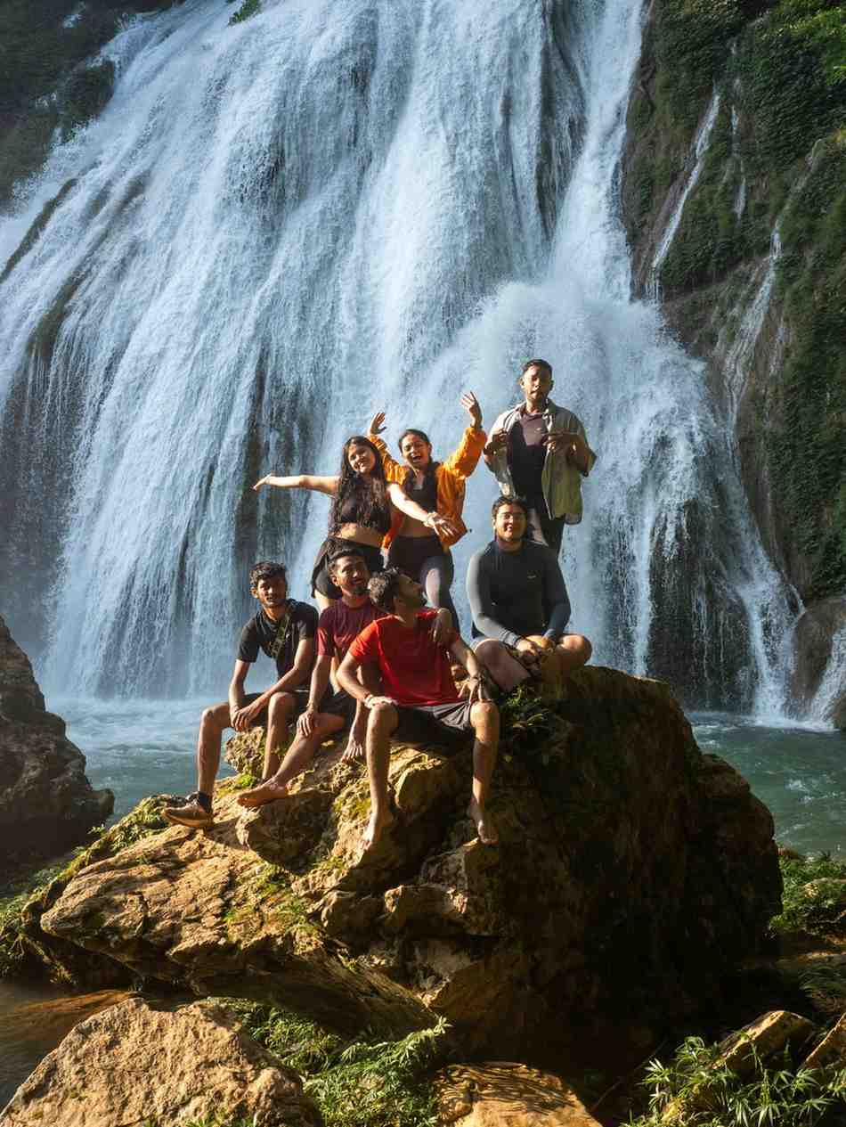 Group of friends posing on rocks near a waterfall