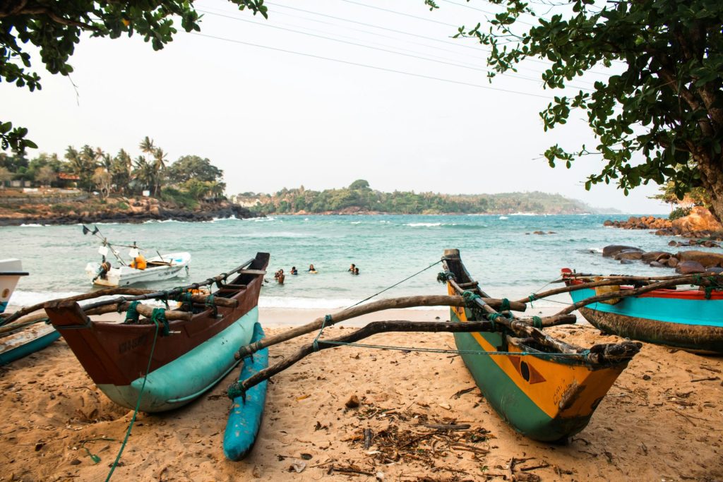 Boats sit on a beach with the ocean in the background